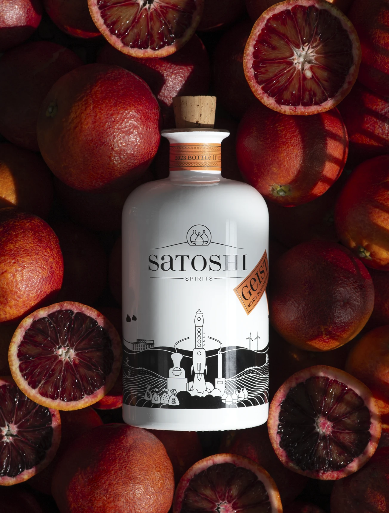 Ein Korb voller frischer Blutorangen und einer Flasche Satoshi Blutorangengeist